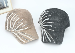 Detailed view of champagne and dark grey baseball caps with pearl and rhinestone patterns