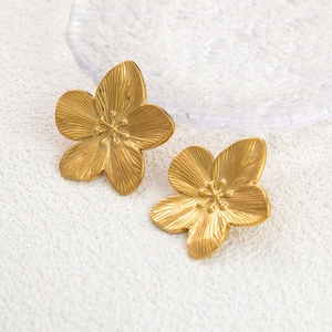 Macro shot of 18K gold-plated titanium steel flower earrings with fine metallic texture