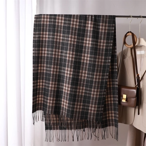 Close-up of dark plaid cashmere-like scarf with fringe hanging on a rack in a studio