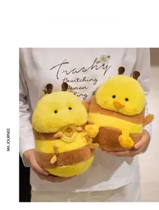 Close-up of cute plush bee toys with soft fur texture held by a model for scale