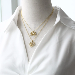 Elegante collana con pendente a fiocco dorato con zirconi su un modello con camicia bianca