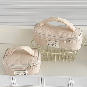 Detailed view of beige quilted makeup bags with top handles in two practical sizes