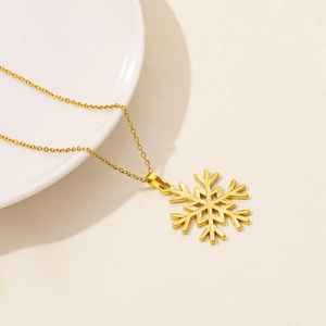 Detailed macro view of the golden snowflake pendant on a minimalist stainless steel chain