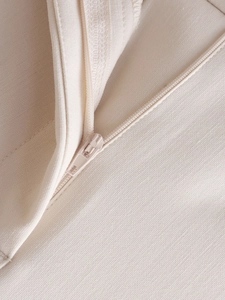 Detailed macro view of beige fabric texture with a high-quality matching zipper closure