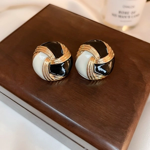 Boucles d'oreilles nœud vintage dorées avec émail noir et crème en gros plan élégant