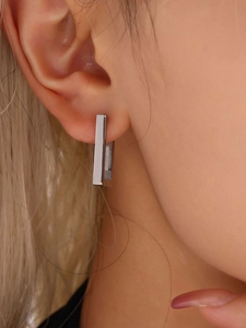 Close-up of a model wearing silver rectangular stainless steel geometric earrings