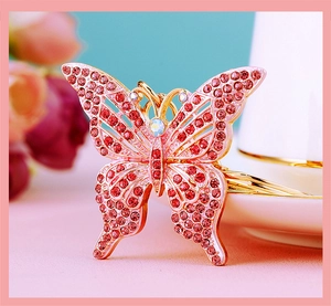 Macro view of golden metal butterfly keychain with pink and red rhinestone details