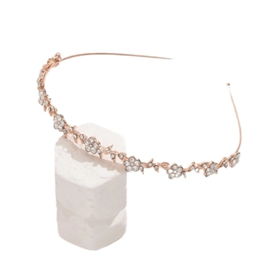 Elegant rose gold flower headband with rhinestones and crystals on a white marble stand