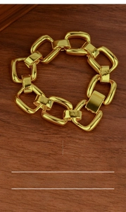 Detail of chunky gold-plated chain bracelet with 20.5cm length on a wood surface