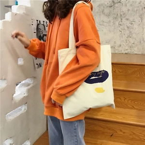 Close-up of beige canvas tote bag featuring abstract color blocks and text art