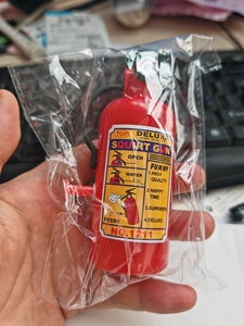 Detailed view of red mini fire extinguisher squirt gun toy in clear plastic packaging