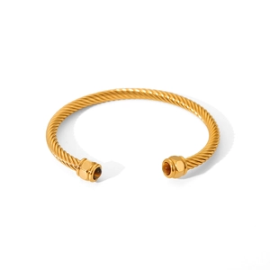 Detail of gold twisted cable cuff bracelet with tiger eye stones on white background