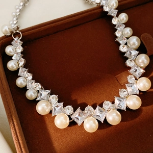 Detailed view of luxury pearl necklace with diamond accents in a brown jewelry box