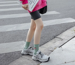 Street style shot of mid-calf green socks with embroidery paired with grey sneakers
