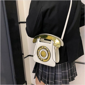 Detailed view of a retro dial phone crossbody bag with gold handset handle and sequins