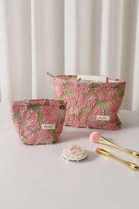Detailed view of pink floral embroidery and fringe texture on a green makeup bag set