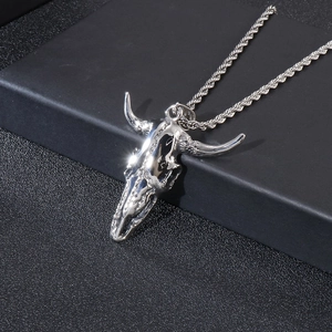 Detailed close-up of a silver punk bull skull pendant necklace on a matte black stand