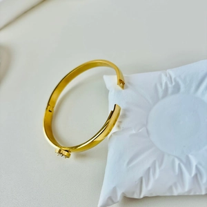 Detail of gold-plated bangle featuring a round clasp pave-set with white cubic zirconia crystals