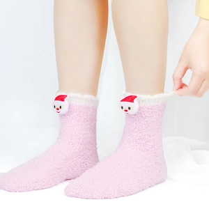 Detailaufnahme der rosa Korallenvlies-Socken mit 3D-Weihnachtsmann-Plüschfiguren
