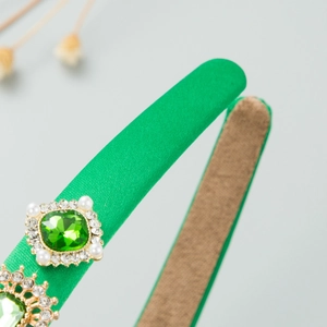 Detail of emerald gemstone and pearls on green satin baroque style headband accessory