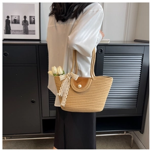 Detail of straw tote bag with brown leather flap, pearl clasp and white lace ribbon