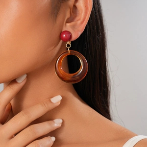 Détail des boucles d'oreilles rétro en résine avec perles rouges et anneaux ambrés