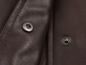 Macro shot of dark brown faux leather texture with metal snap button and stitching details
