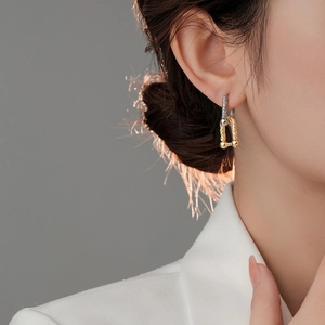 Close-up of model wearing two-tone horseshoe U-shaped chain earrings in gold and silver