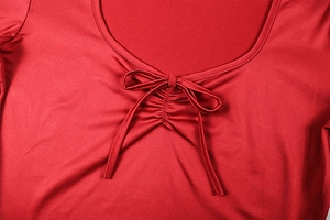 Detail of red dress neckline featuring a stylish bow tie and delicate pleated design