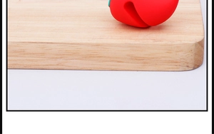 Detail shot of a red carrot lid lifter in silicone resting on a wooden cutting board