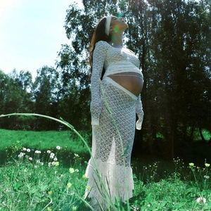 Detail of white maternity lace set featuring sheer long sleeves and textured floral pattern