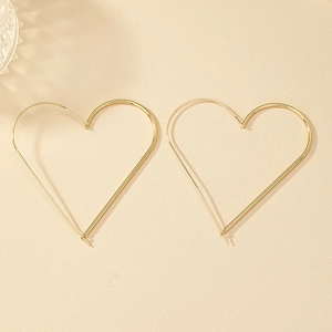 Macro shot of minimalist gold heart-shaped hoop earrings on a warm textured background