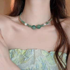 Dettaglio della collana di perle verdi con pietre irregolari e fiori argentati