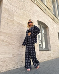 Detail of loose-fit black button-down shirt and high-waist trousers with geometric pattern