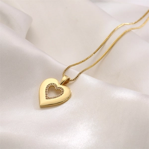 Gold heart pendant necklace with shimmering zircon stones on a white silk background