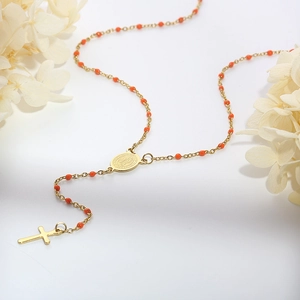 Detail of gold rosary necklace with orange beads, Mary medal and cross pendant