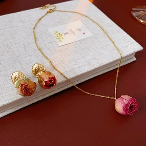 Vintage handmade rose jewelry set with gradient pink petals and gold chain on books