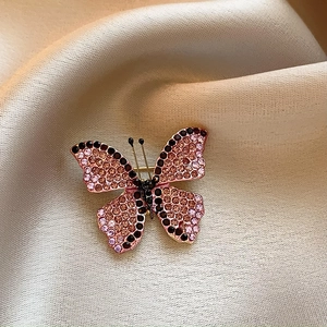 Macro shot of butterfly brooch with purple and pink rhinestones on silk fabric