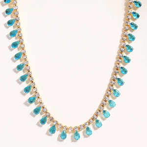 Macro shot of gold necklace featuring teardrop blue crystals and white zircon accents