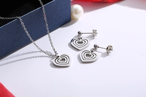 Detail of silver hollow multi-layer heart necklace and earrings set with red ribbon