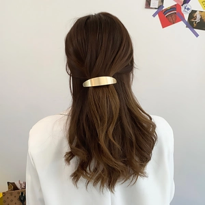 Minimalist gold metal spring hair clip for women shown on a stylish ponytail hairstyle