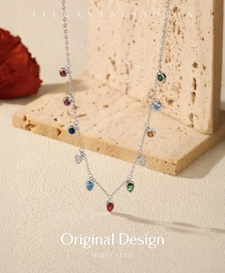 Detail of S925 silver necklace with multi-colored gemstones against a stone background