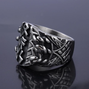 Macro shot of Viking runes relief on vintage stainless steel ring over black reflective surface