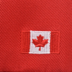 Macro shot of high-quality red maple leaf embroidery on Canada baseball cap fabric