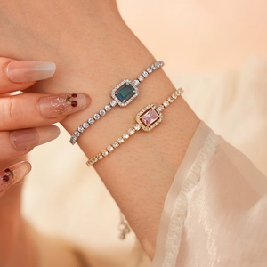 Detail of adjustable bracelets with rectangular blue and pink zircon stones on wrist