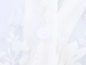Close-up of white mesh fabric with floral embroidery and a round button detail