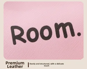 Dettaglio macro della pelle Saffiano rosa con scritta Room su una borsa per cosmetici