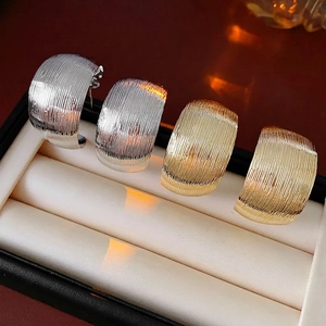 Elegant gold and silver C-shaped ribbed earrings in luxury minimalist jewelry display