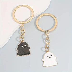 Close-up of black and white enamel ghost charms with gold-plated chains and keyrings