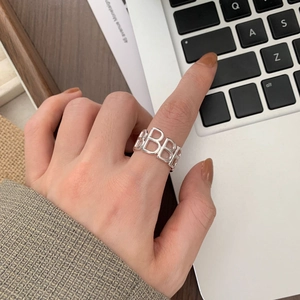 Close-up of a 925 sterling silver hollow letter B ring worn on an index finger